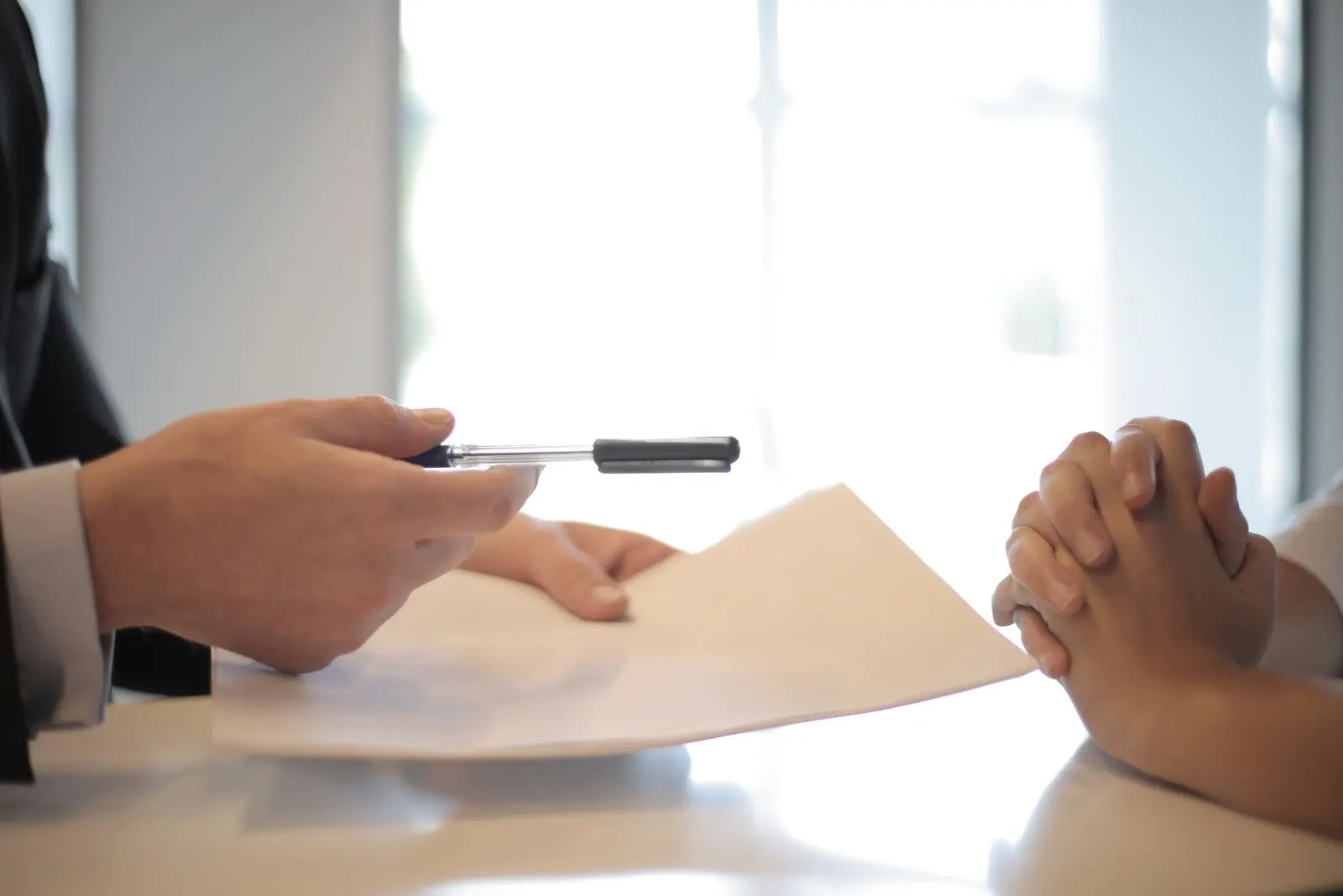 Profissional de RH entregando documentos a candidato durante processo de admissão